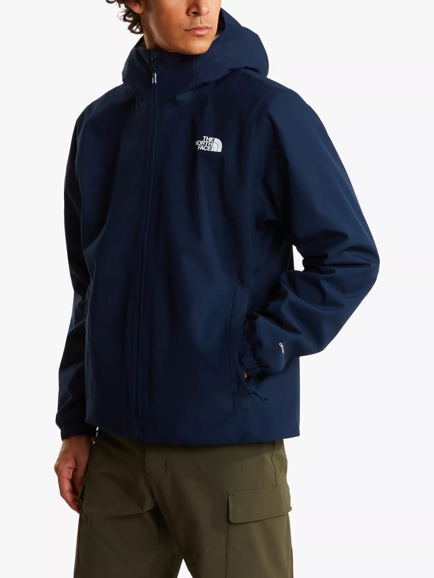 A man wearing a navy blue hooded jacket with a white embroidered The North Face logo on the left chest, paired with olive green cargo pants, against a plain white background.