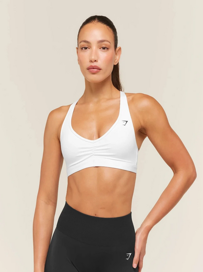 Woman wearing a white sports bra and black leggings on a beige background