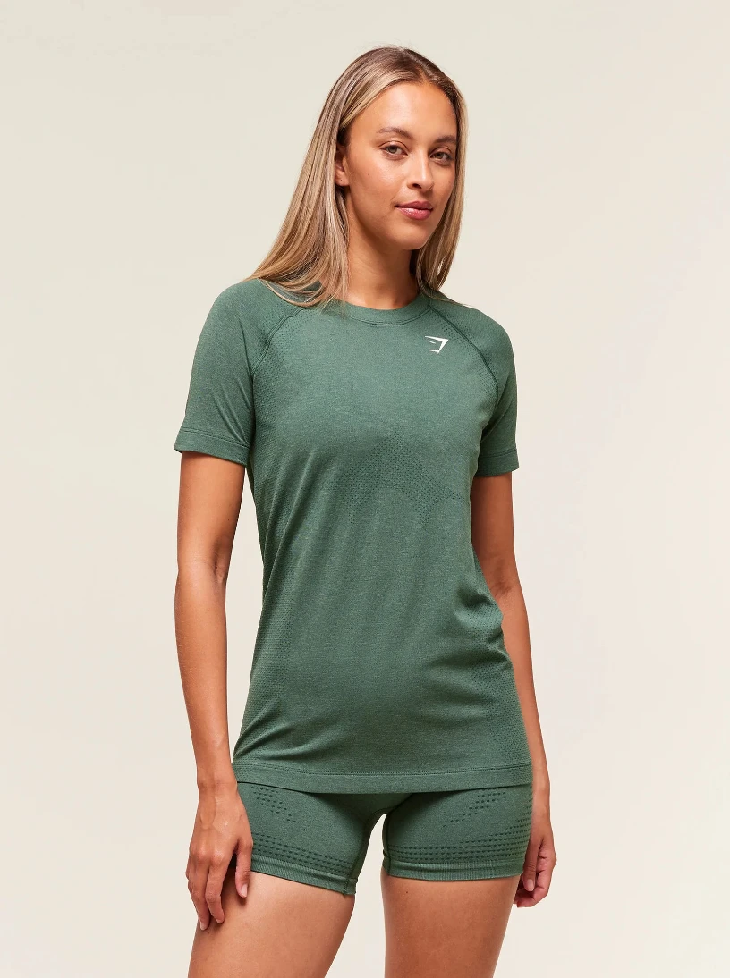 Woman wearing a green athletic outfit with a logo on a beige background