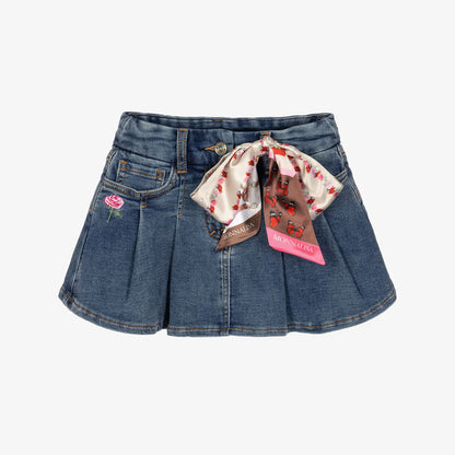 A pair of blue denim shorts featuring pleated detailing, a pink embroidered rose on the left pocket, and a decorative silk bow with a floral print and a pink Morvillo brand tag.