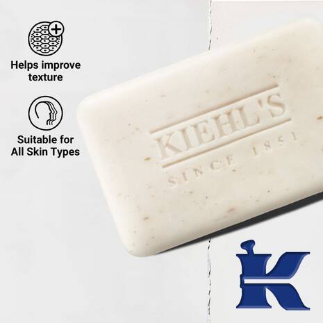 A bar of Kiehl's skincare soap shown on a white background with product benefits text on the left and a blue Kiehl's logo in the bottom right corner.